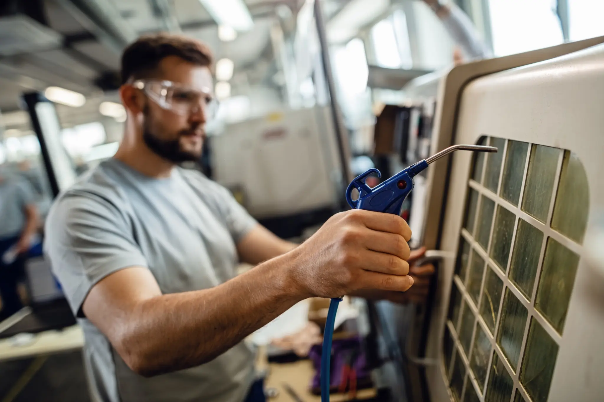 Technician cleaning an HVAC unit with compressed air