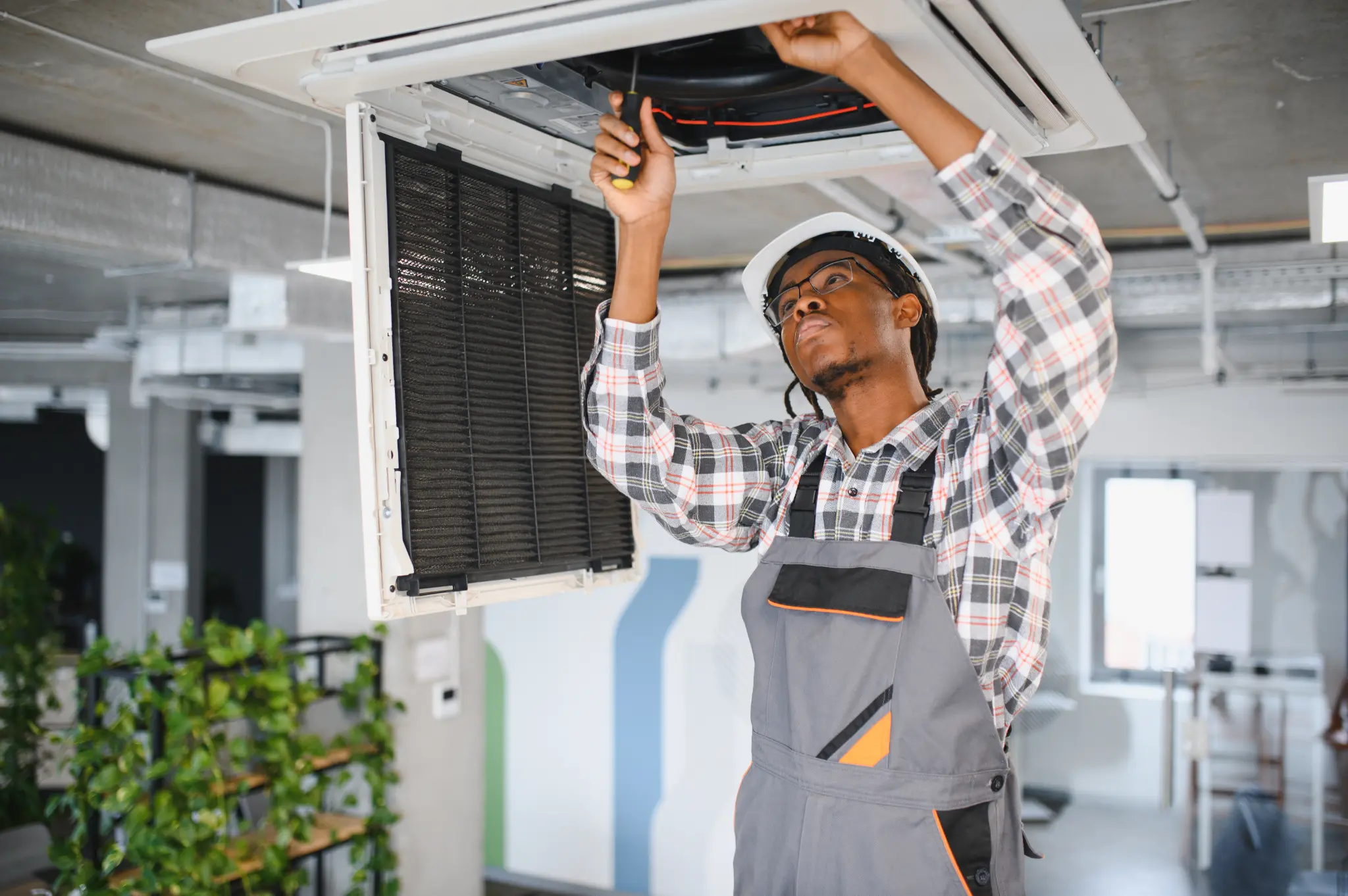 Technician servicing a ceiling-mounted air conditioning unit