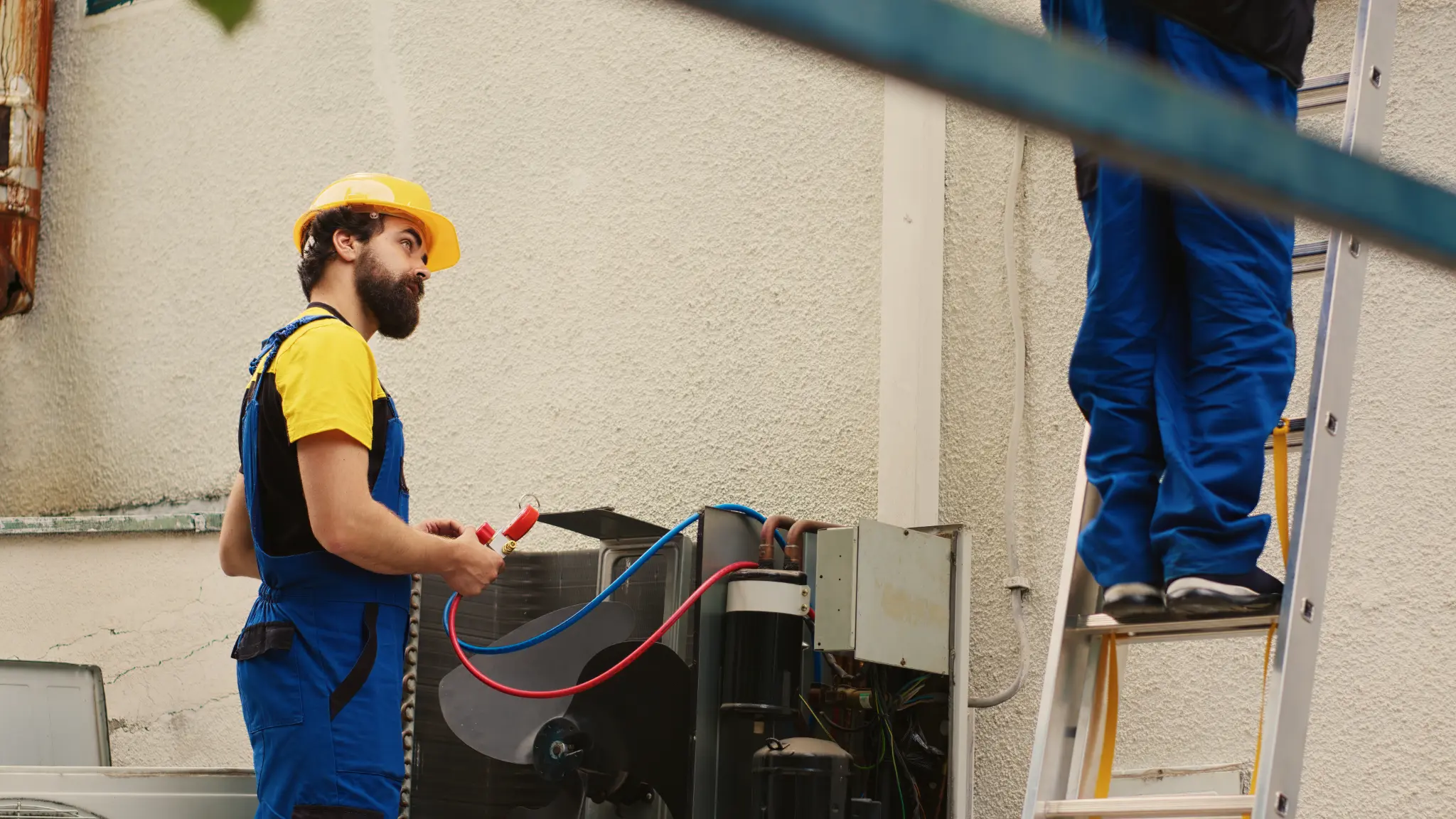 Two HVAC technicians inspecting an outdoor air conditioning system