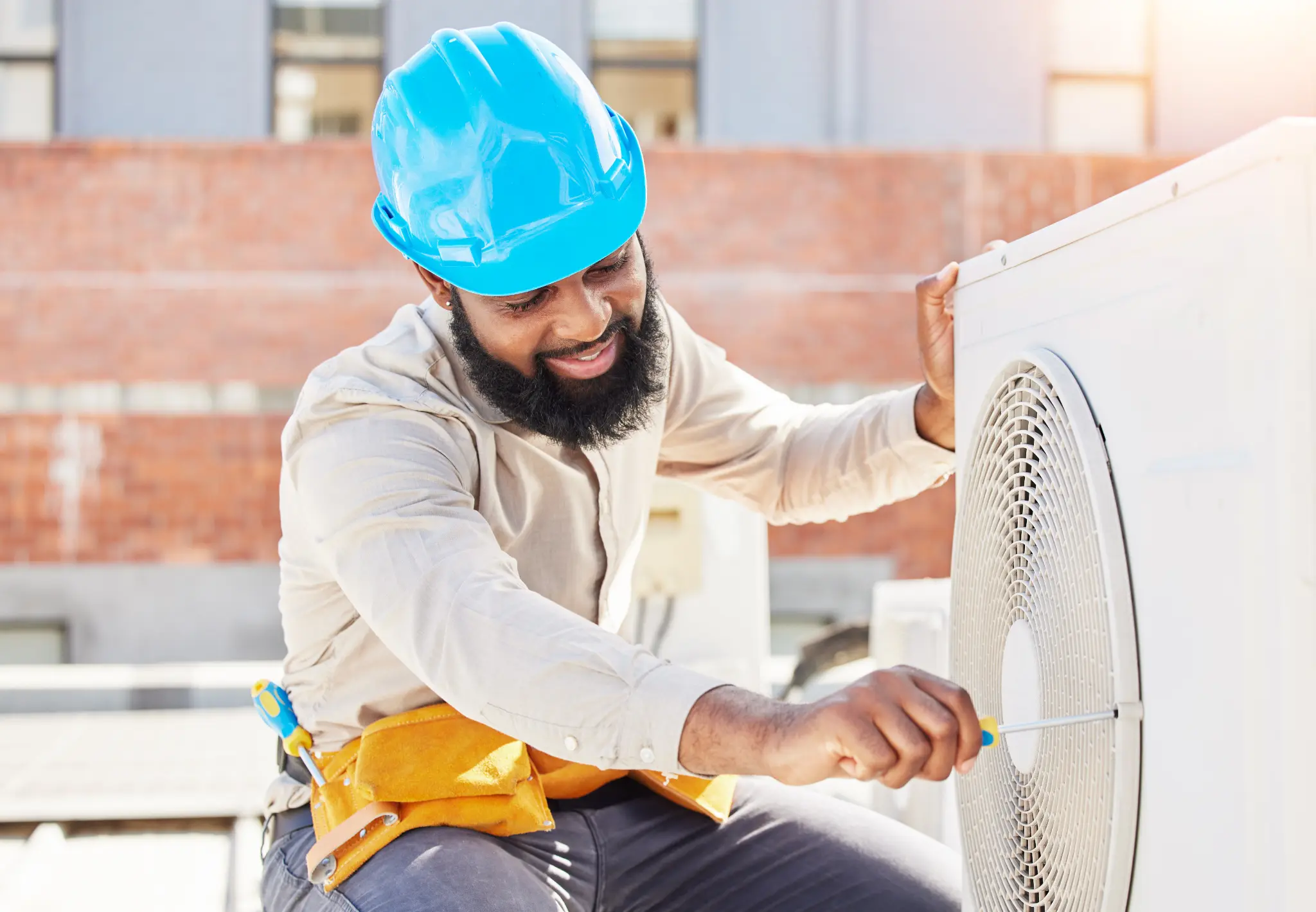 HVAC technician using a screwdriver on an outdoor air conditioner